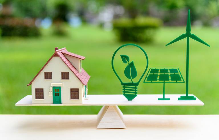 Une maison sur une balance avec des symboles Energie verte